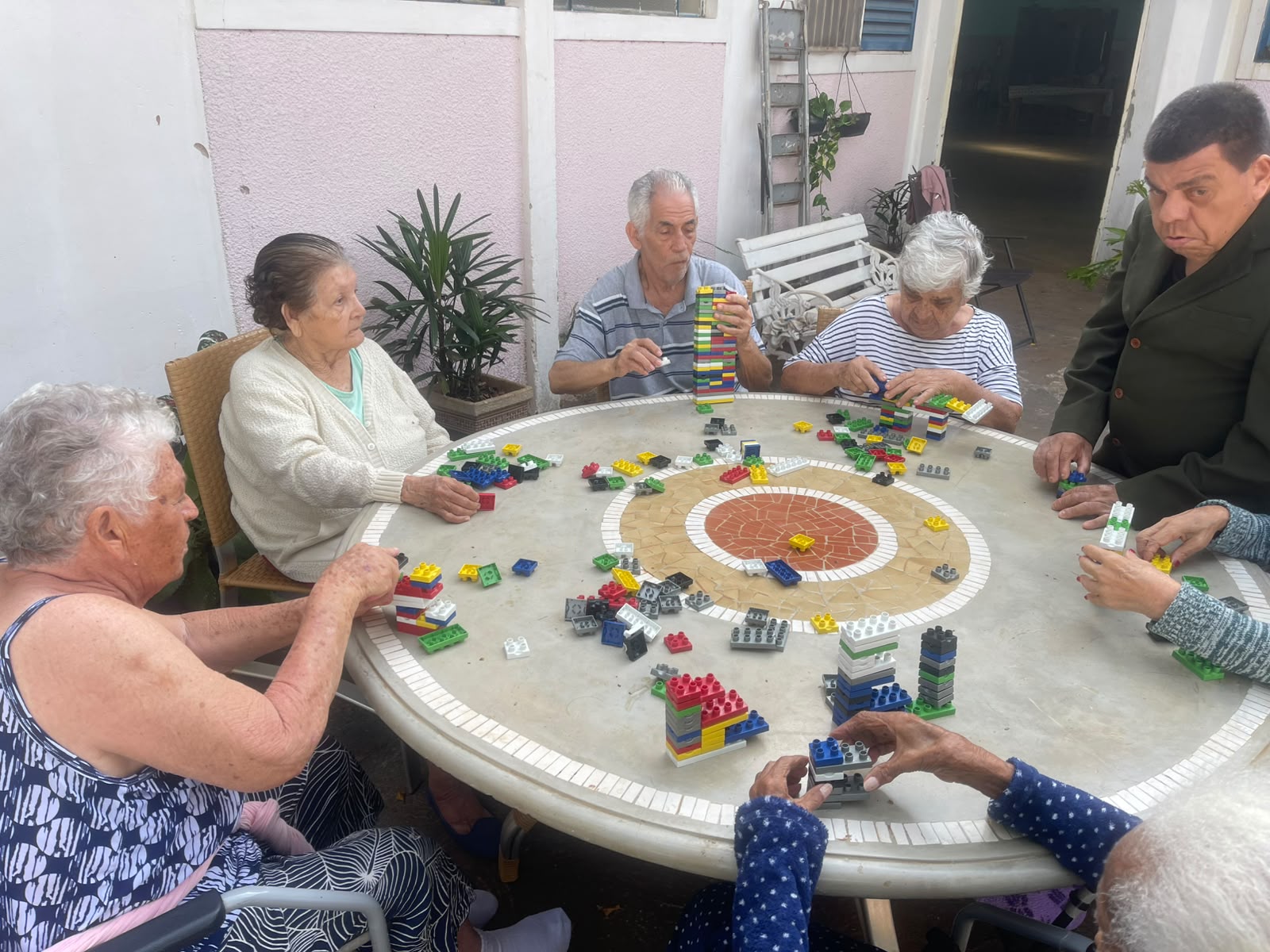 Residentes ao redor de uma mesa montando torres com blocos de encaixe coloridos
