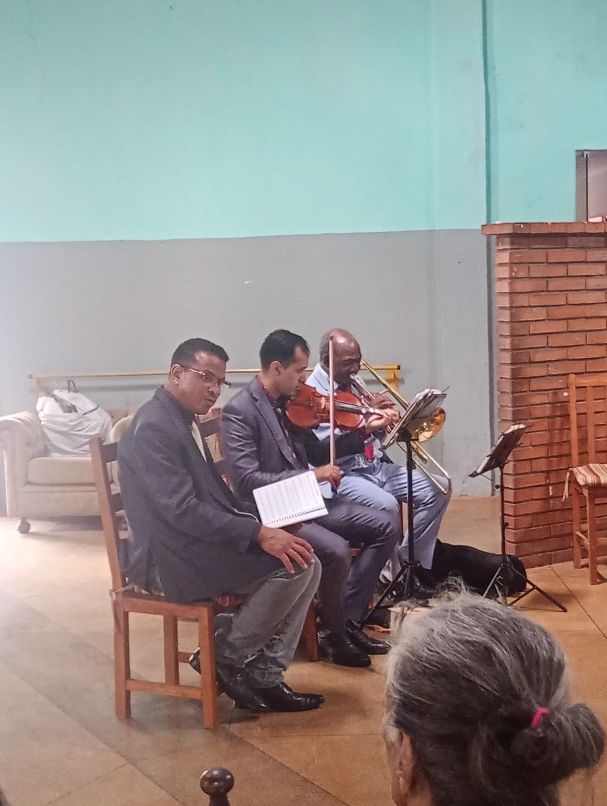 Músicos tocando violino e trombone para os residentes no salão da casa